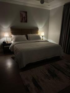 a bedroom with a large white bed with two lamps at شقه بتصميم فاخر وراقي-حي السلامة in Jeddah