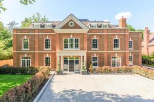 a large red brick house with a driveway at Luxury 3 Bed Penthouse with Large Terrace and Private Parking in Sunningdale