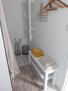 Una habitación blanca con un banco con toallas encima. en Agréable chambre pour 2 avec salle de bain et terrasse privées, en Fagnières