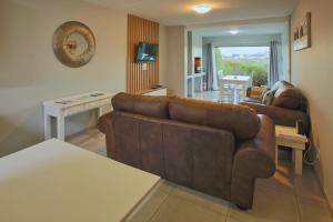 a living room with a brown couch and a table at Bella Casa, Langebaan, 4-sleeper in Langebaan