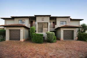 a house with two garage doors on a brick driveway at Bella Casa, Langebaan, 4-sleeper in Langebaan