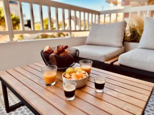 a table with a bowl of fruit and two glasses of juice at Le Cattleya in Dinard