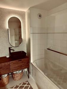 a bathroom with a tub and a sink and a mirror at Le Cattleya in Dinard +9 photos