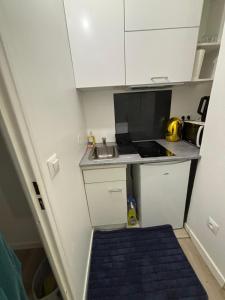 a small kitchen with white cabinets and a sink at Studio Bethel cosy à Villejuif centre Paris in Villejuif