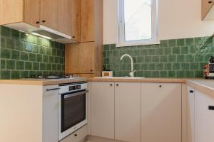 a kitchen with white cabinets and green tiles at TripON cozy spot in Cluj-Napoca