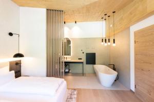 a bedroom with a tub and a bed and a desk at ELVA PREMIUM APARTMENT HOTEL inklusive Sommerpass STUBAI SUPER CARD in Neustift im Stubaital