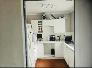 a small kitchen with white cabinets and a refrigerator at The Chardonnay Inn in Centurion