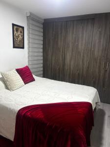 a bedroom with a large bed with a red blanket at Aptosvacacionales Medellín in Medellín