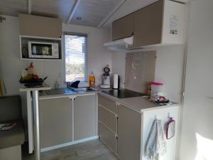 eine Küche mit weißen Schränken und einer Spüle in der Unterkunft mobil home premium 6 personnes très confortable climatisé in Montagnac