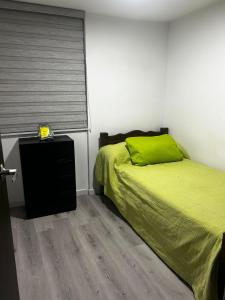 a bedroom with a green bed and a window at Aptosvacacionales Medellín in Medellín