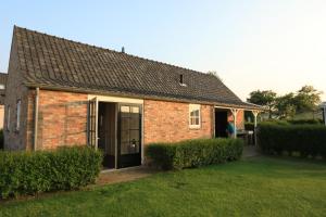 Una casa de ladrillo con su puerta abierta en un patio. en Pipowagen, en Serooskerke 2 fotos más