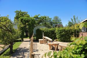 un jardín con banco, mesa y árboles en Pipowagen, en Serooskerke