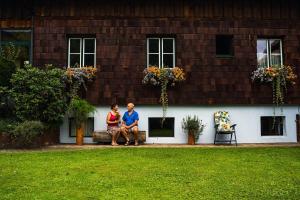 a man and woman sitting on a bench in front of a house at Ferienholzhaus in Sankt Gallen im Gesäuse in der Steiermark in Sankt Gallen +8 photos
