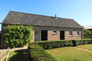 una casa de ladrillo con un seto delante en Pipowagen, en Serooskerke