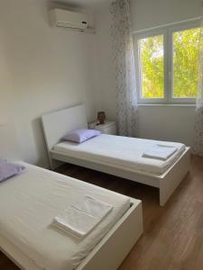 two beds in a room with a window at Apartments Pepi in Mali Lošinj +26 photos