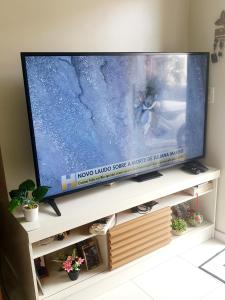 une grande télévision à écran plat assise sur une table de télévision dans l'établissement Apato em Condomínio, à Belém
