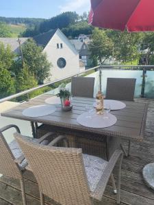 シュマレンベルクにあるFerienwohnung Dickのデッキの上に置かれた木製のテーブル、椅子、傘