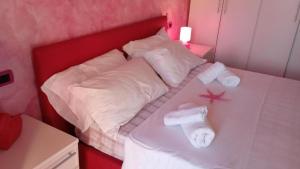 een wit bed met handdoeken en een rood hoofdeinde bij Noemi House & Rooms in Novara +4 foto's