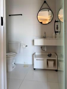 a bathroom with a toilet and a sink and a mirror at Perfect Campolim loft in Sorocaba