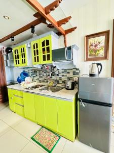 a kitchen with yellow and green cabinets and a refrigerator at Studio Nami - Horizons 101 in Cebu City