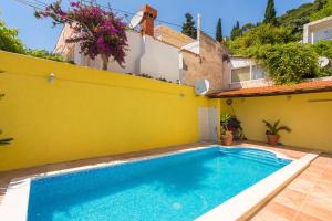 a pool in the backyard of a house with a yellow wall at Central Apartment in Dubrovnik