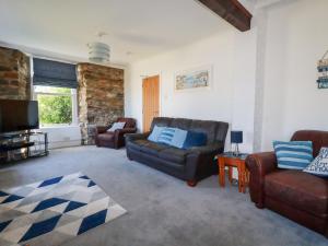 a living room with two couches and a flat screen tv at Tregundy Farmhouse in Perranporth