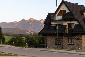 ein Haus mit schwarzem Dach mit Bergen im Hintergrund in der Unterkunft Apartamenty Koziniec Lux in Czarna Góra