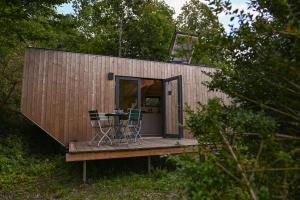 a small house with a table and chairs on a deck at Tiny House Pioneer 6 - Green Tiny Village Harz in Osterode