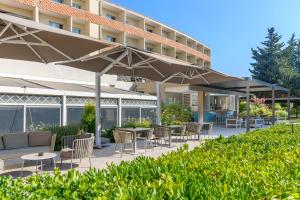 un patio extérieur avec des tables et des chaises sous un parasol dans l'établissement Crowne Plaza Rome St. Peter's by IHG, à Rome