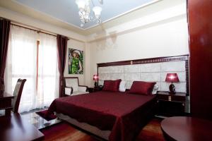 ein Schlafzimmer mit einem großen Bett mit einer roten Tagesdecke in der Unterkunft Orchidea Hotel in Tirana