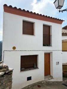 a white house with three windows and a door at Estudi d art i natura in Villahermosa del Río