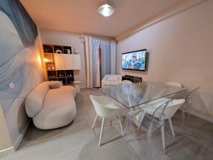 a dining room with a glass table and white chairs at San Lorenzo Exclusive in San Lorenzo al Mare