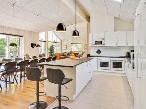 a kitchen with white cabinets and a bar with chairs at 5 star holiday home in Fjerritslev in Fjerritslev
