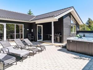 a patio with chairs and a hot tub next to a house at 5 star holiday home in Fjerritslev in Fjerritslev +35 photos