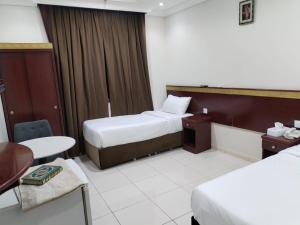 ein Hotelzimmer mit zwei Betten und einem Tisch in der Unterkunft تولب الفضي in Az Zahrāʼ