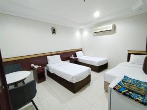 ein Hotelzimmer mit zwei Betten und einem Stuhl in der Unterkunft تولب الفضي in Az Zahrāʼ