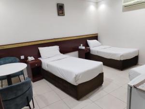 ein Hotelzimmer mit zwei Betten und einem Tisch in der Unterkunft تولب الفضي in Az Zahrāʼ