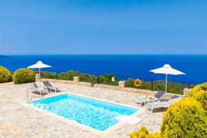 a swimming pool with chairs and umbrellas and the ocean at Villa Valio in Dhrapanítika