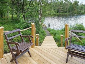 two benches sitting on a wooden deck next to a lake at 8 person holiday home in Hyltebruk in Hyltebruk