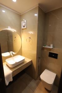 a bathroom with a sink and a toilet and a mirror at Nexstay Hotel Calicut Gate in Kozhikode