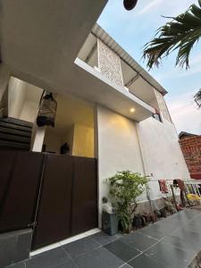 une maison blanche avec un portail et un palmier dans l'établissement Pasuruan heritage guest house, 