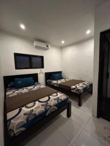 une chambre avec deux lits et une télévision au mur dans l'établissement Pasuruan heritage guest house, 