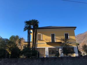 a yellow building with a palm tree in front of it at Villa Corfù in Ponte Brolla