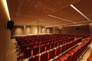 an empty auditorium with red seats in a room at Nexstay Hotel Calicut Gate in Kozhikode