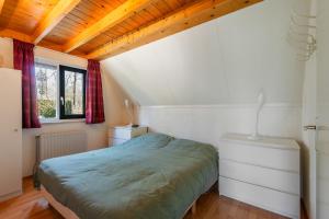 a bedroom with a bed and a wooden ceiling at Lovely bungalow with woodburner and airco in Zwiggelte