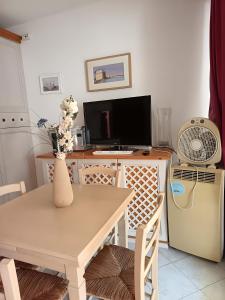 a dining room with a table and a television at Rex Lo Scoglietto Punta Ala in Punta Ala