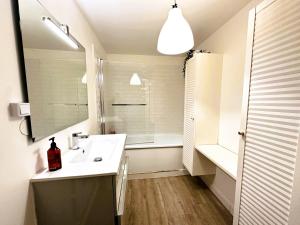 a white bathroom with a sink and a mirror at Eugène - Elégance & Confort in Reims +6 photos