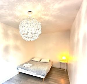 a bedroom with a bed and a chandelier at Eugène - Elégance & Confort in Reims