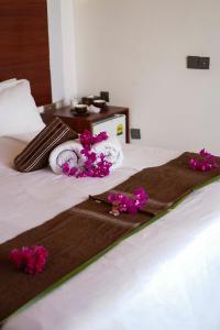 a bed with towels and purple flowers on it at Valley Palm Seaview in Guraidhoo