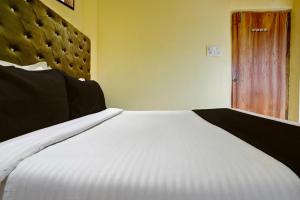 a large white bed in a room with a door at Hotel O Royal Inn in Mumbai